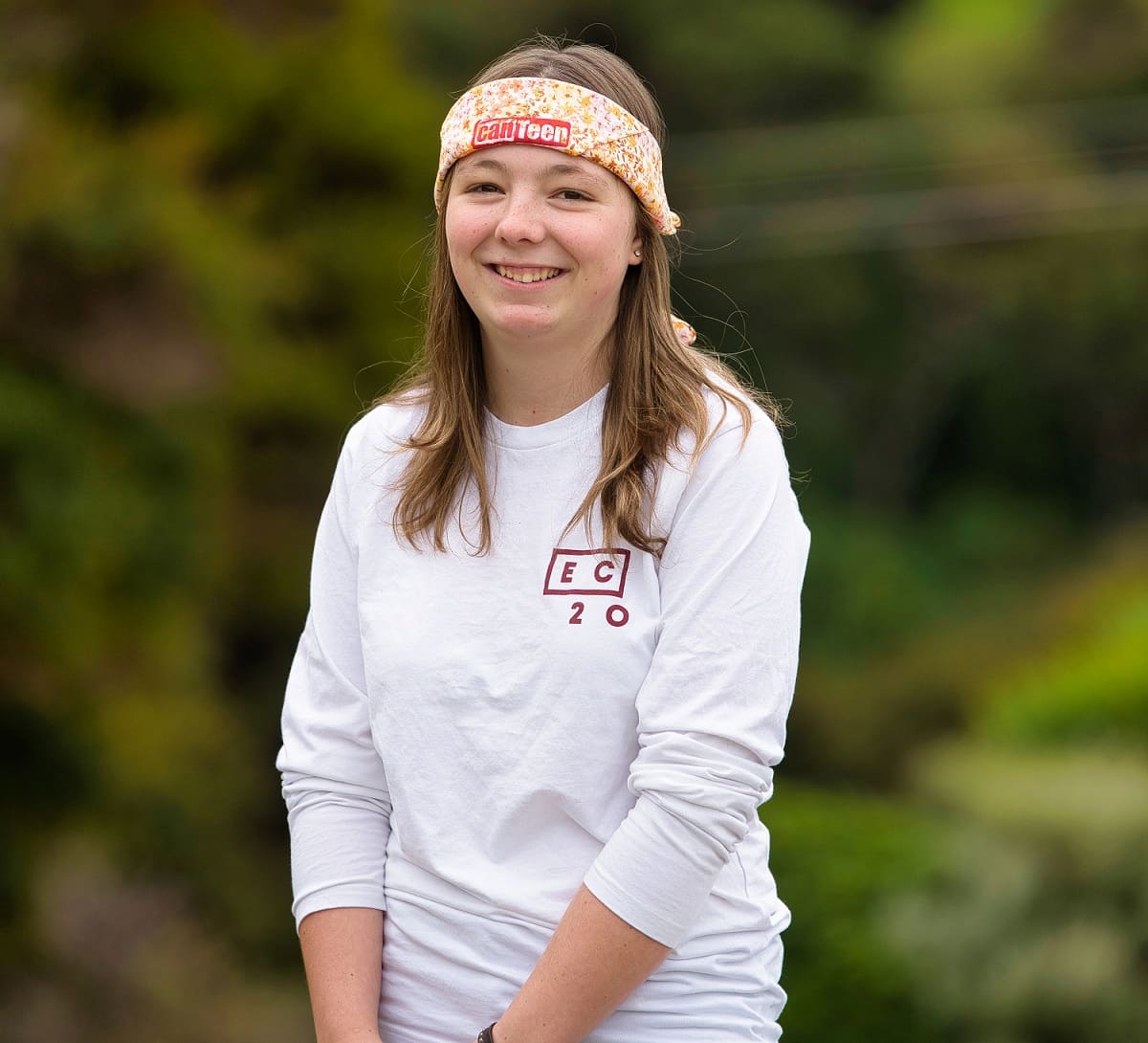 erin wearing a Canteen bandanna and a white long sleeved tshirt. she is smiling at the camera