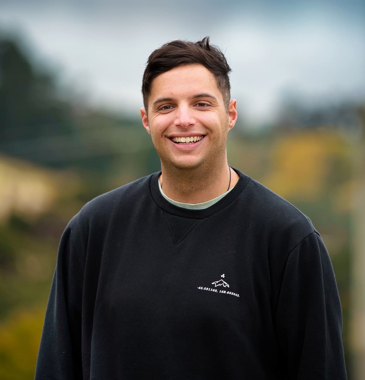 hirini wearing a black long sleeved shirt and smiling at the camera