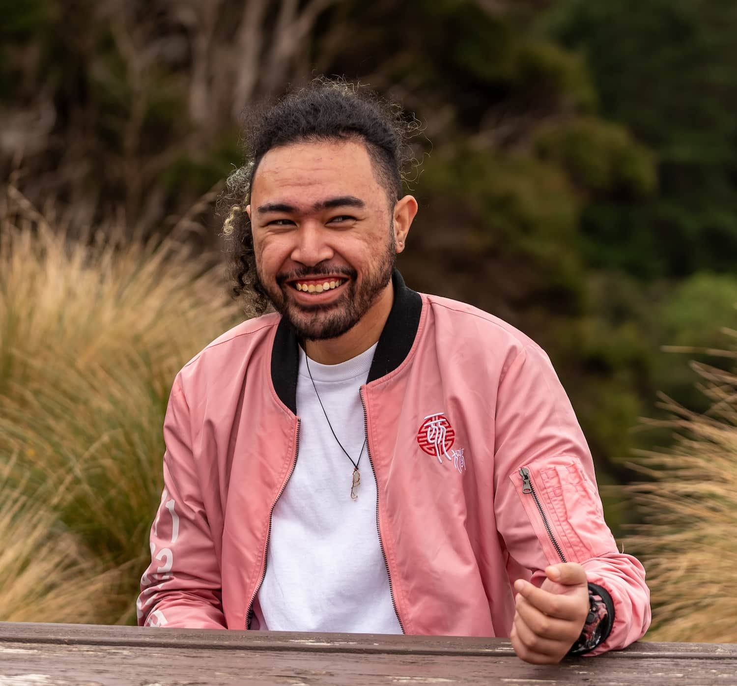 leaton wearing a pink jacket and white shirt smiling at the camera