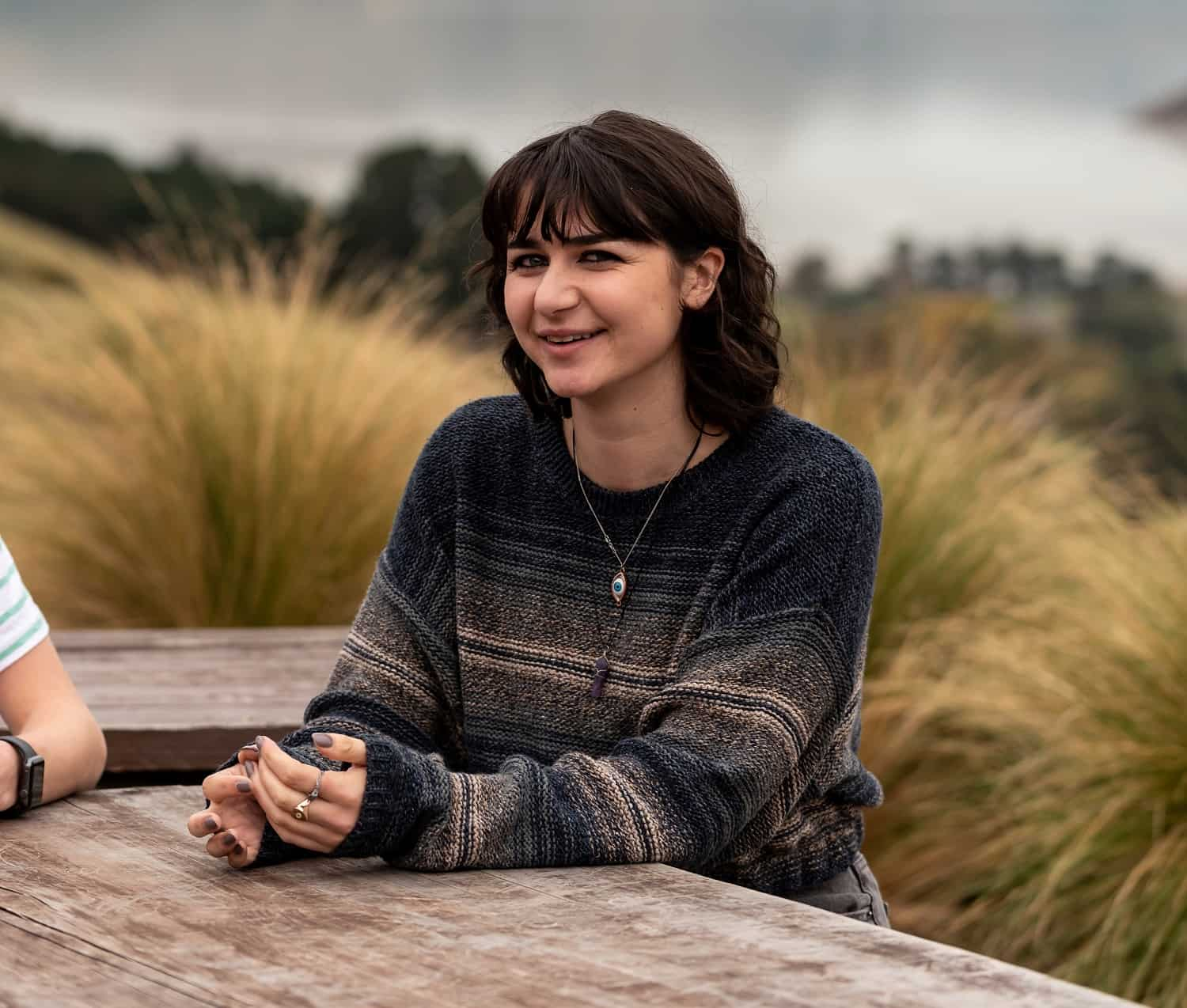 teri sitting at a wooden table with her arms in front of her. she is smiling at the camera