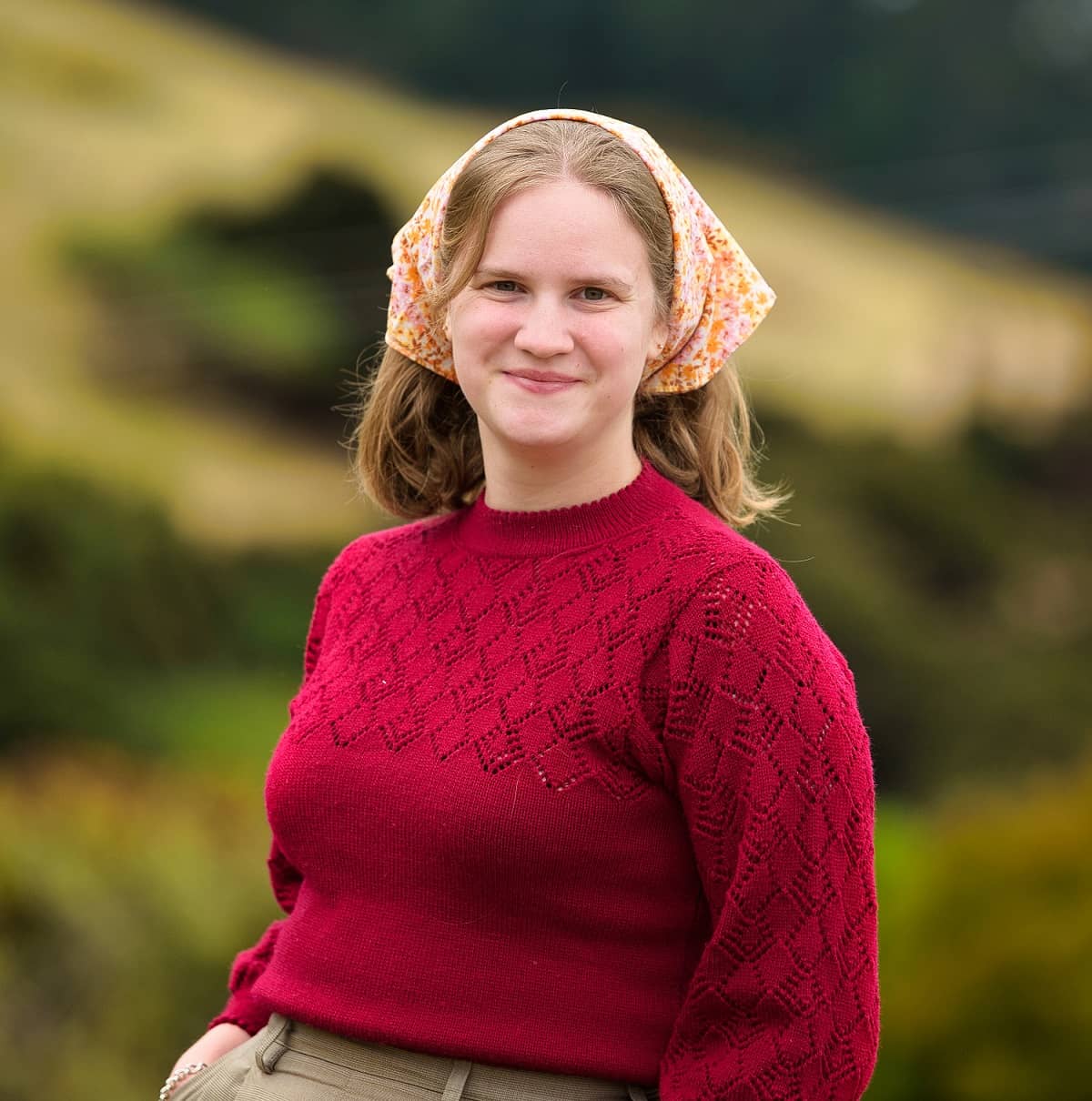 tui wearing a canteen bandanna and a red sweater. she is smiling at the camera