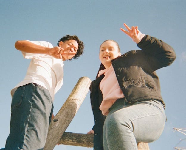 two young people making the peace sign with their hands