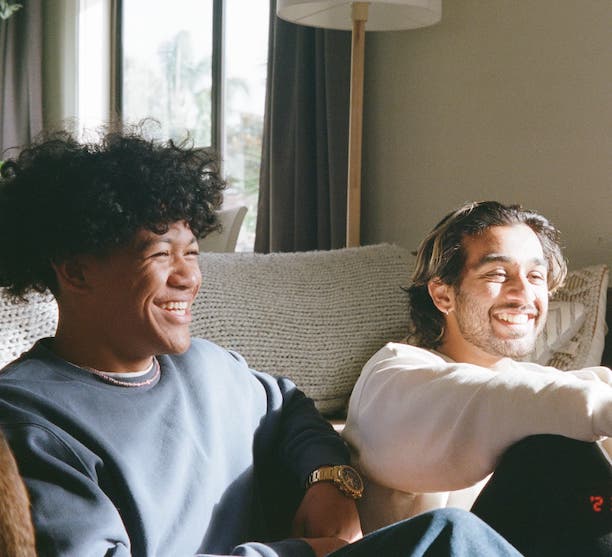 two young people who are receiving support from canteen (the cancer charity) sitting on a couch and laughing