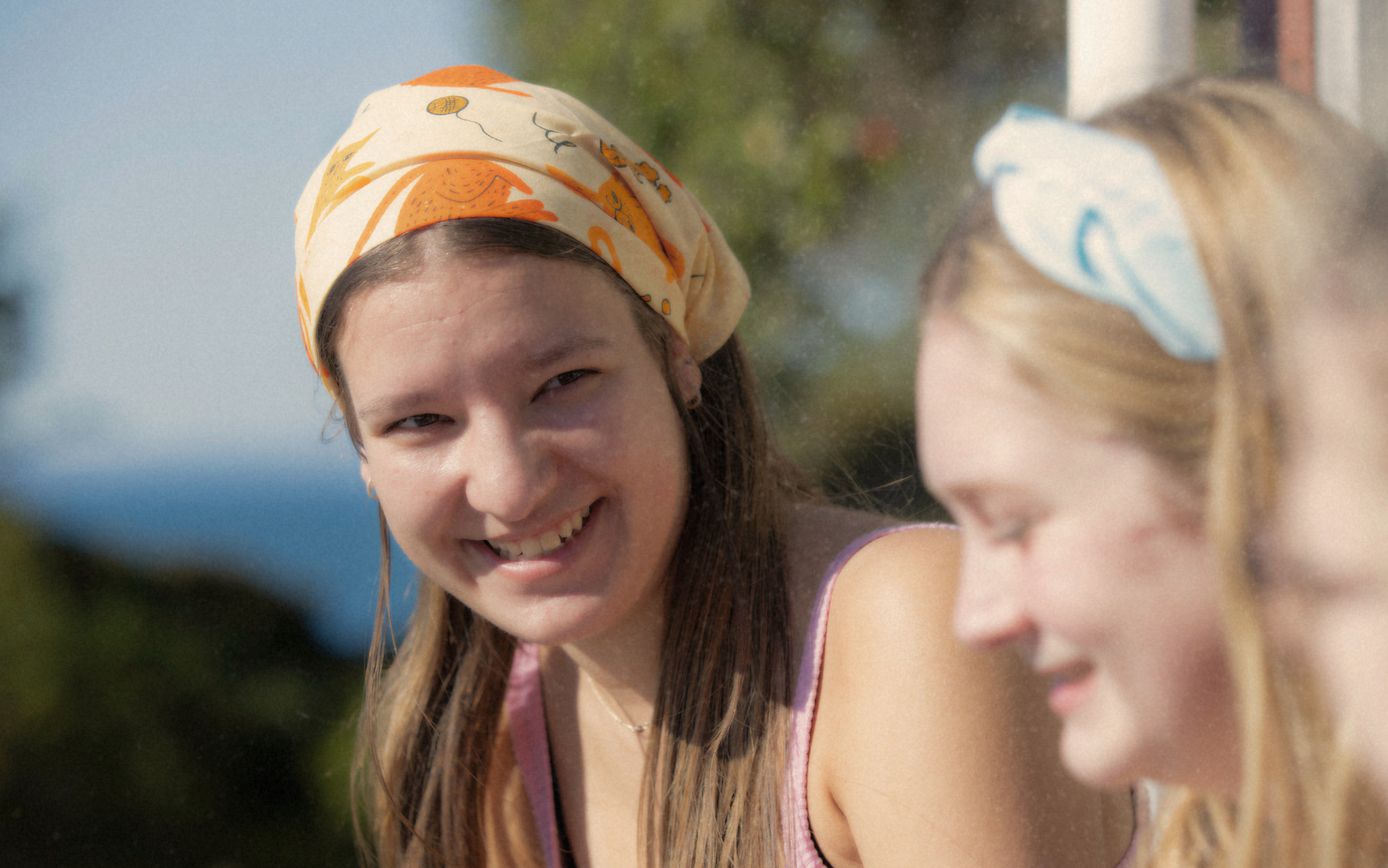 two young people wearing cancer charity canteen bandannas and hugging