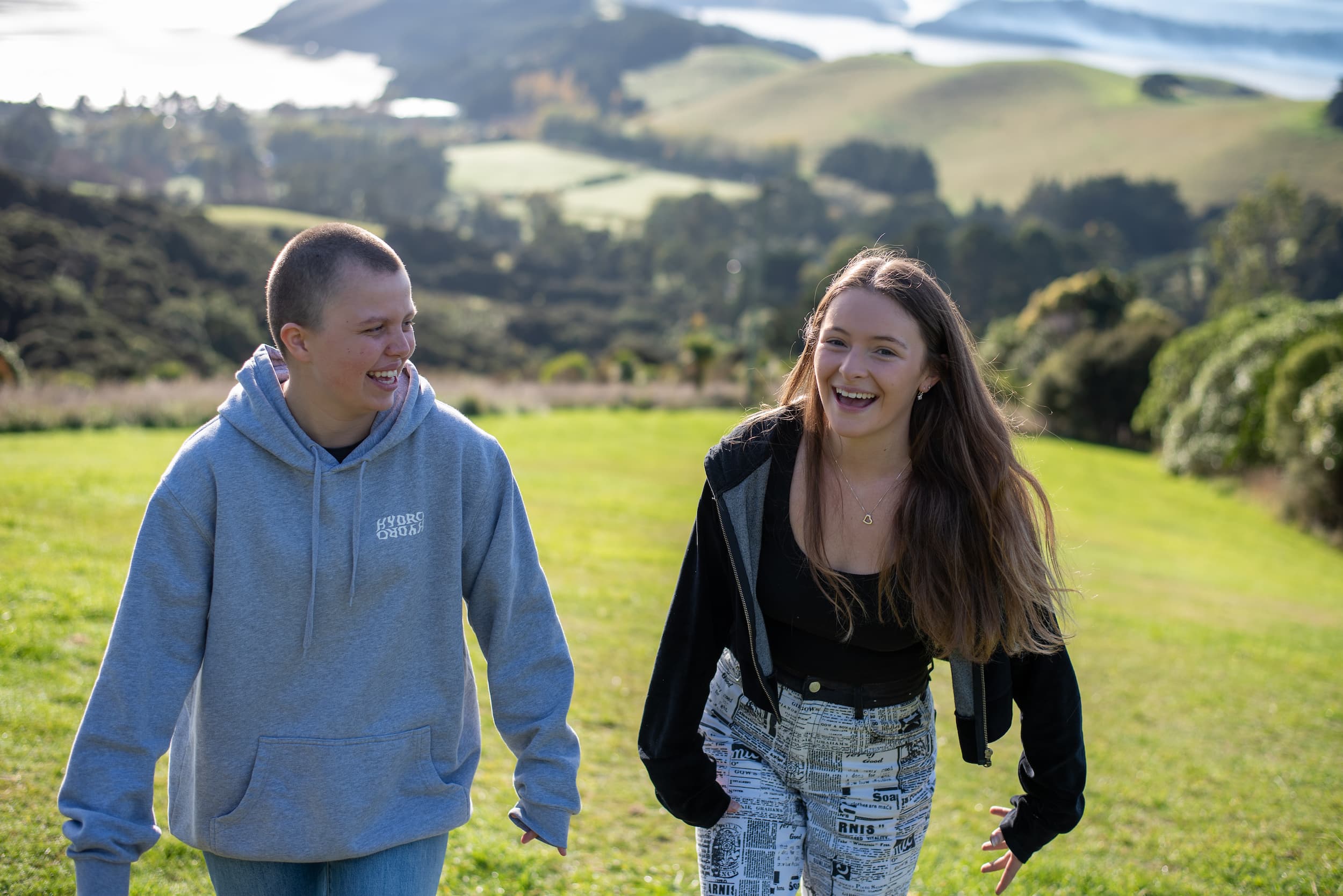 two young people impacted by cancer are walking together and laughing at a canteen program
