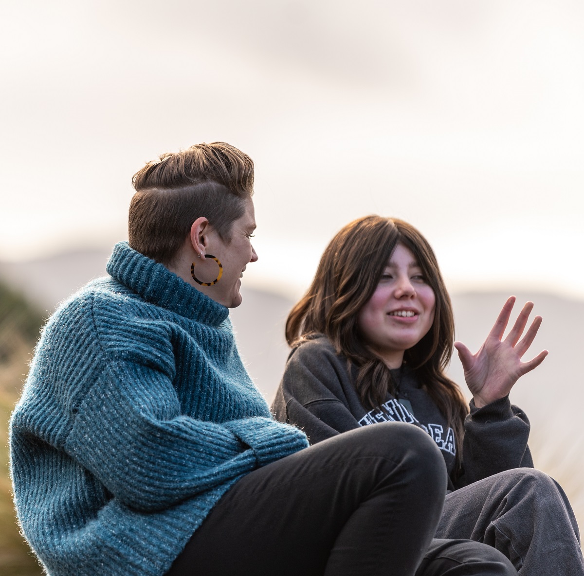 two young people sitting together on the grass and receiving individual support sessions like cancer counselling from canteen