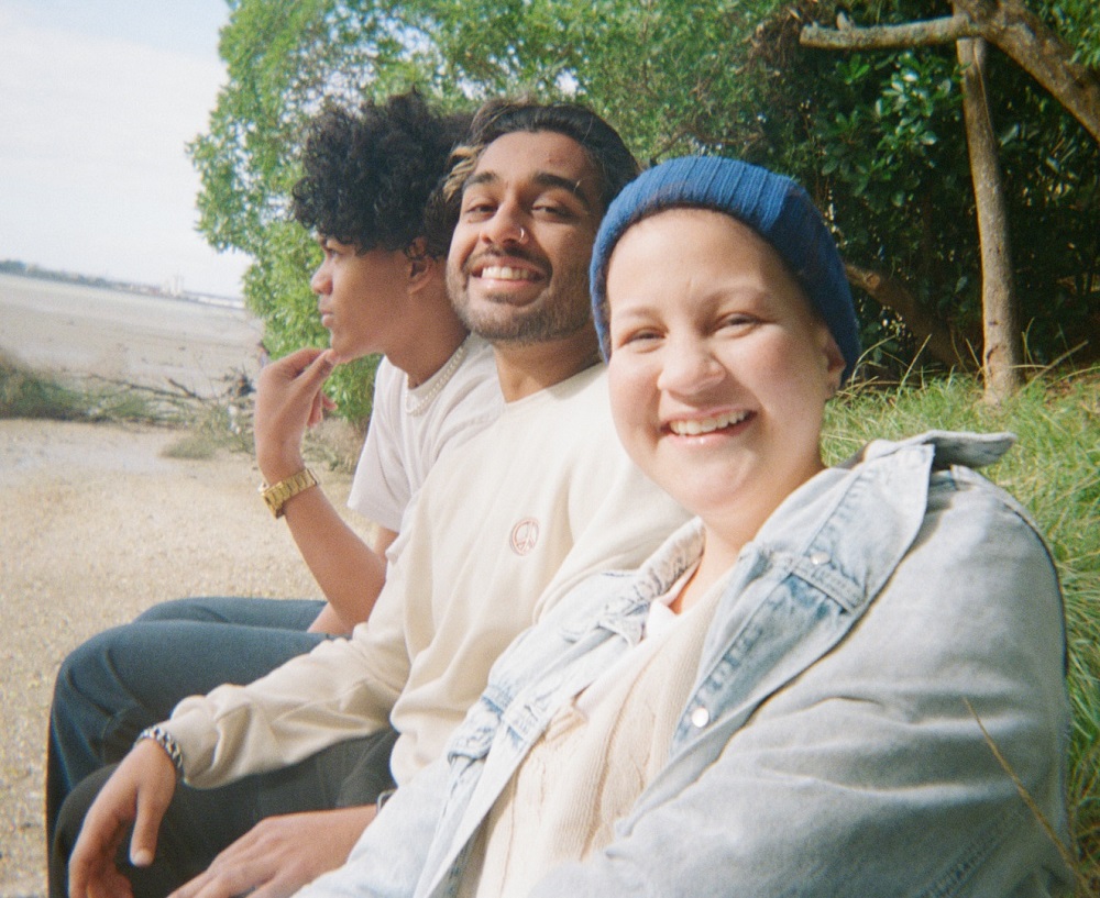 3 young people impacted by teenage cancer or cancer in the family sitting at a park at a peer cancer support event by canteen