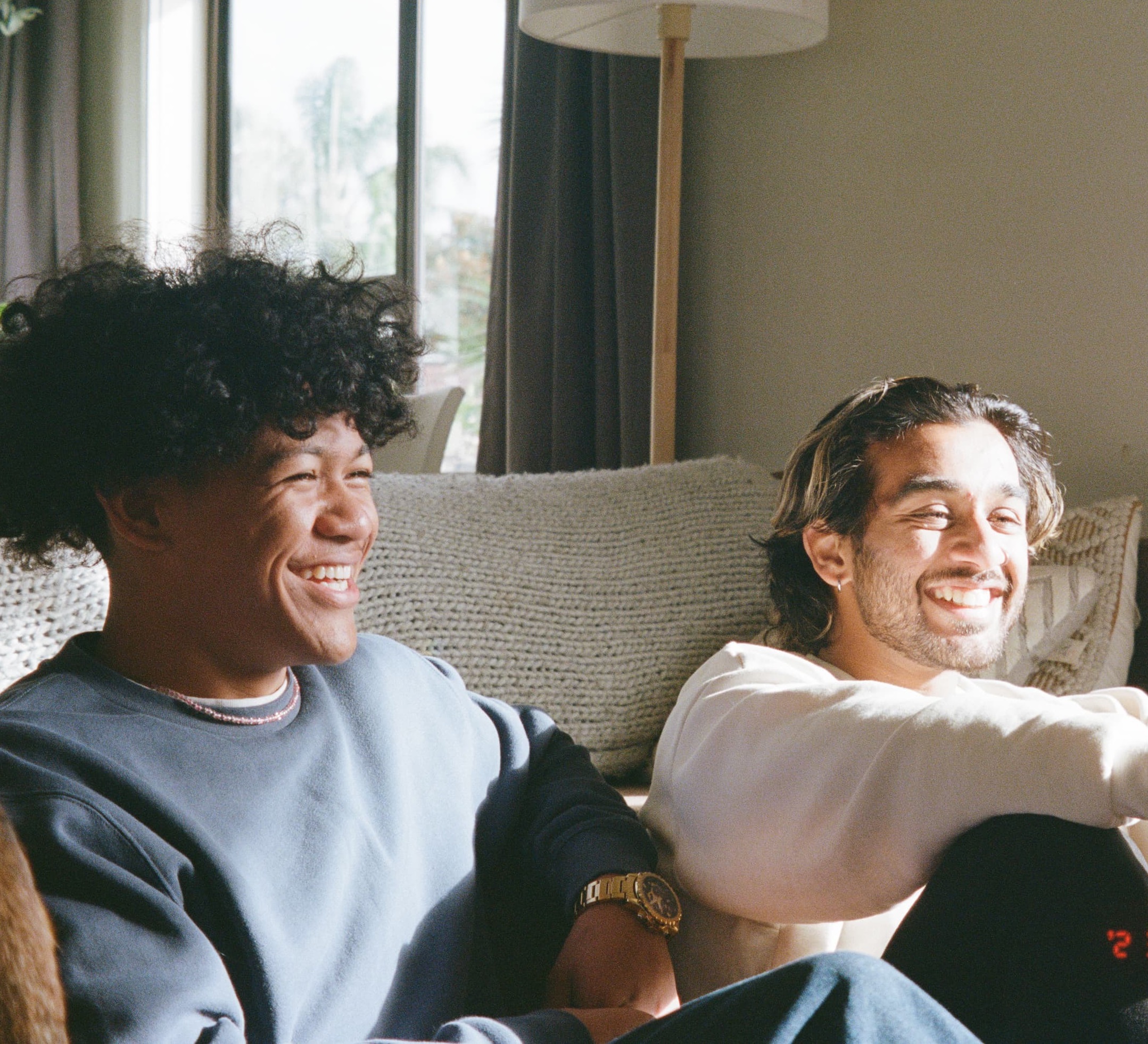 two young people who are receiving cancer support for families and young people are sitting on a couch and laughing