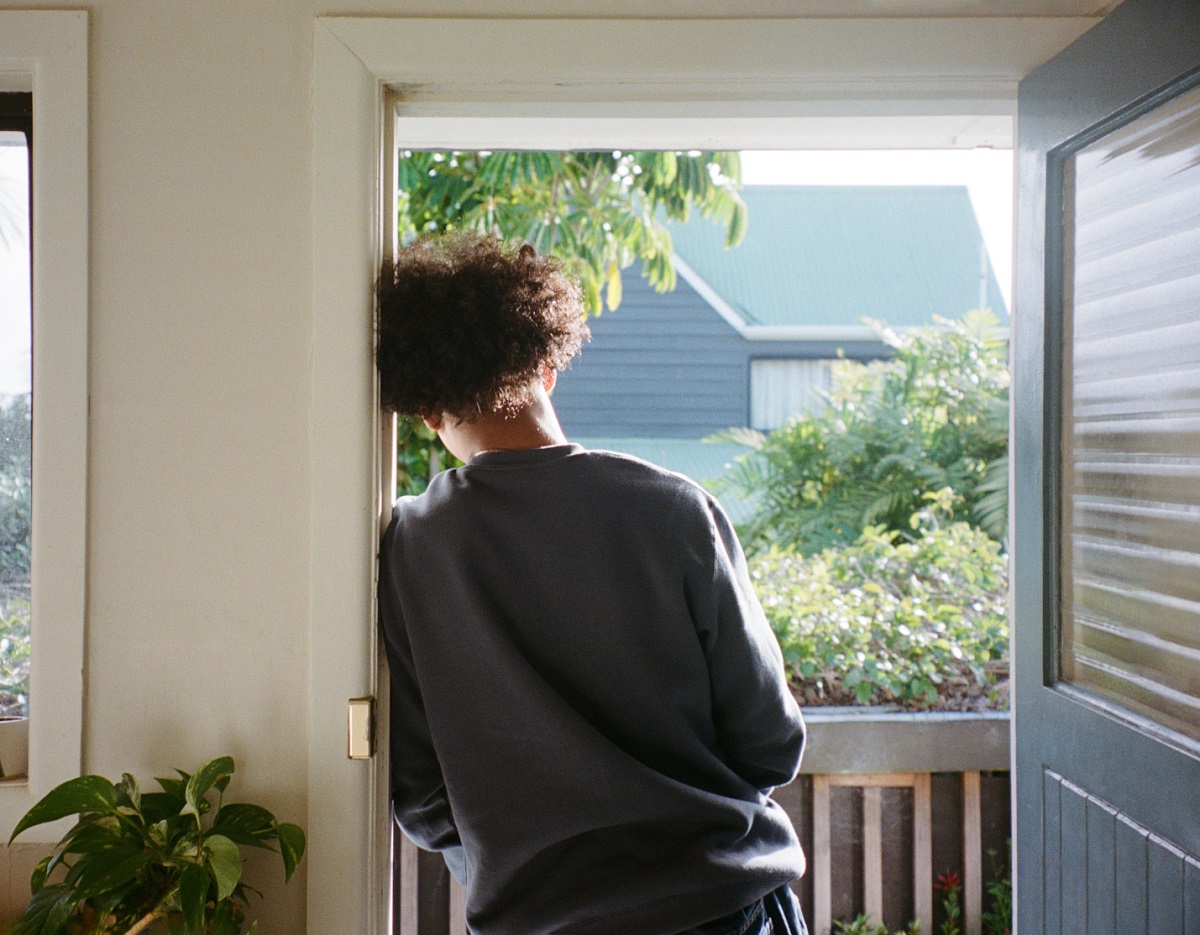 young person leaning at the front door of a house