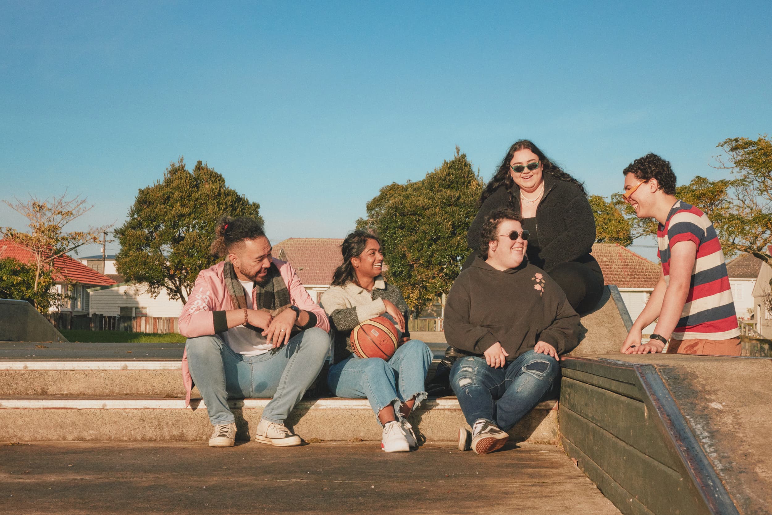 five young people sitting down at a basketball court talking