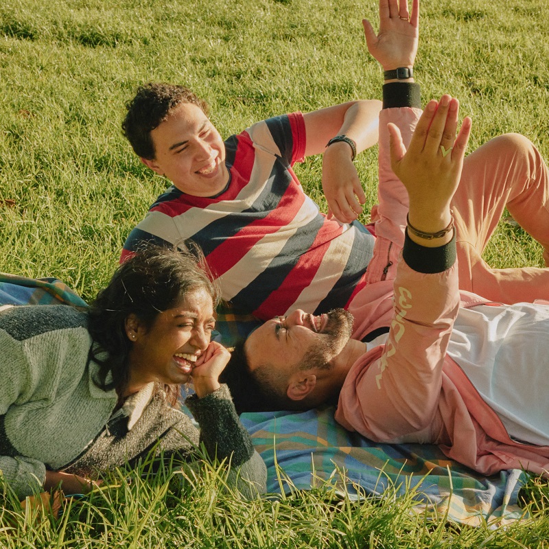 three young people lying on the grass laughing
