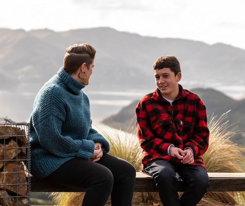 Young person sitting on a bench and talking to someone