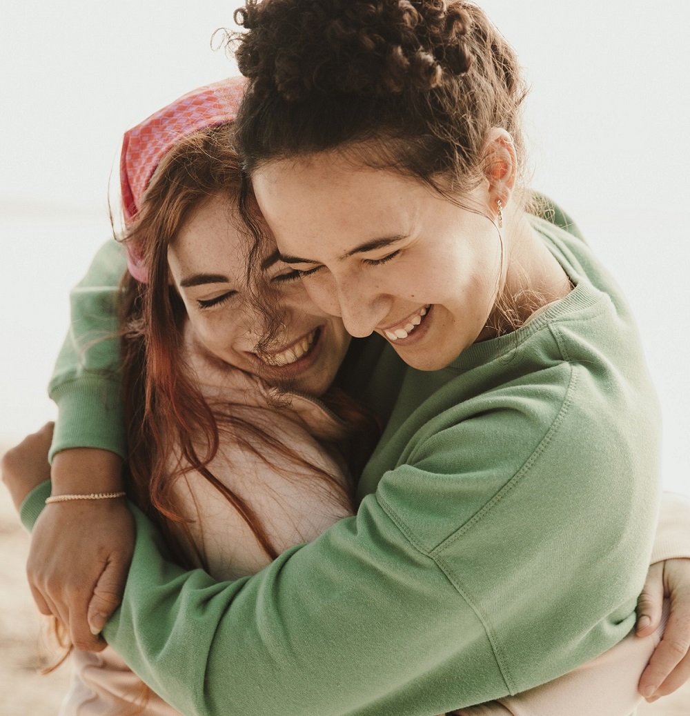 two young people wearing cancer charity canteen bandannas and hugging